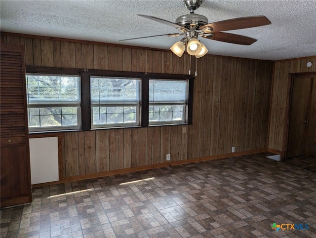 1201 Oblate Dr, Canyon Lake, TX 78133 - empty room featuring brick patterned floors, healthy amount of natural light, wood walls, ceiling fan, and baseboards