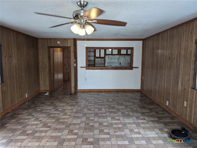 1201 Oblate Dr, Canyon Lake, TX 78133 - unfurnished living room featuring wood walls, baseboards, ceiling fan, brick patterned floors, and a textured ceiling