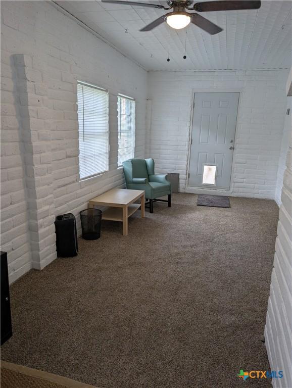 1201 Oblate Dr, Canyon Lake, TX 78133 - sitting room with a ceiling fan, carpet, and brick wall