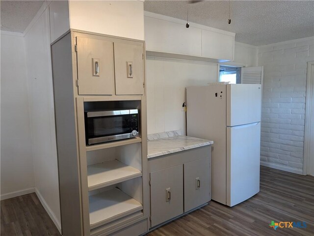 1201 Oblate Dr, Canyon Lake, TX 78133 - kitchen with freestanding refrigerator, stainless steel microwave, a textured ceiling, dark wood-type flooring, and light countertops