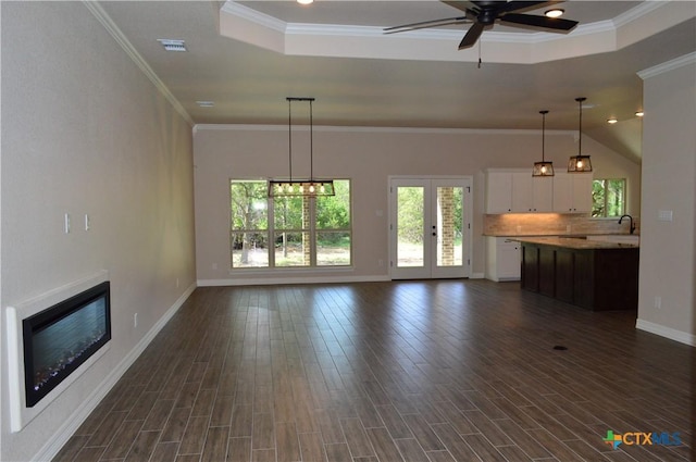 850 County Road 3152, Kempner, TX 76539 - unfurnished living room with a ceiling fan, dark wood-style floors, a tray ceiling, ornamental molding, and a glass covered fireplace