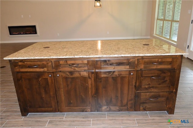 850 County Road 3152, Kempner, TX 76539 - kitchen featuring wood tiled floors, light stone counters, and a warm lit fireplace