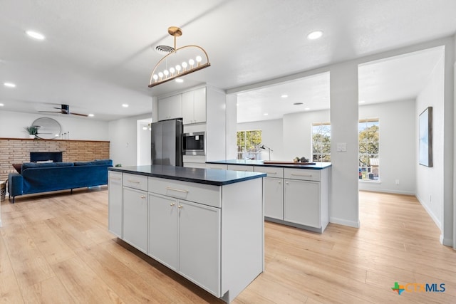 kitchen featuring white cabinetry, hanging light fixtures, light hardwood / wood-style floors, and appliances with stainless steel finishes