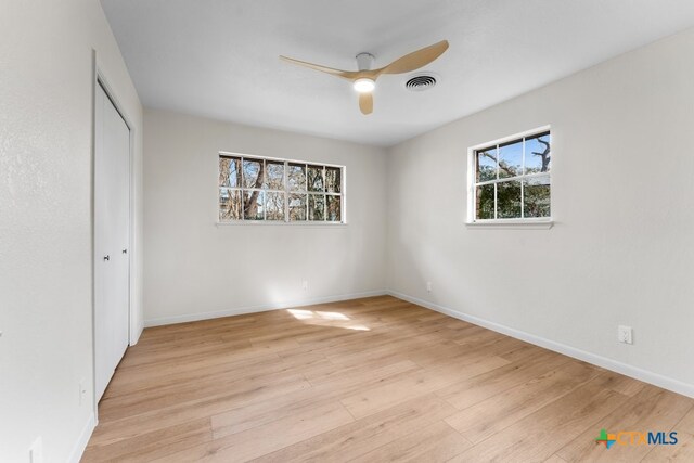 unfurnished bedroom with ceiling fan, a closet, and light wood-type flooring