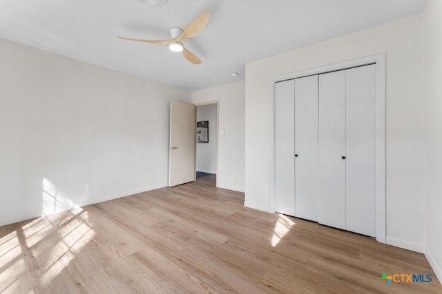 unfurnished bedroom featuring ceiling fan, light hardwood / wood-style floors, and a closet