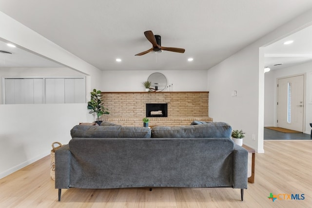 living room featuring a brick fireplace, ceiling fan, and light hardwood / wood-style flooring