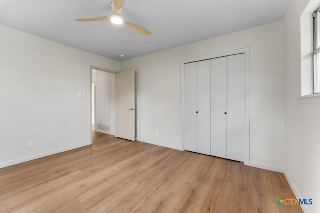 unfurnished bedroom with light hardwood / wood-style flooring, a closet, and ceiling fan