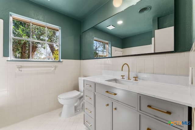 bathroom with vanity, tile walls, tile patterned floors, and toilet