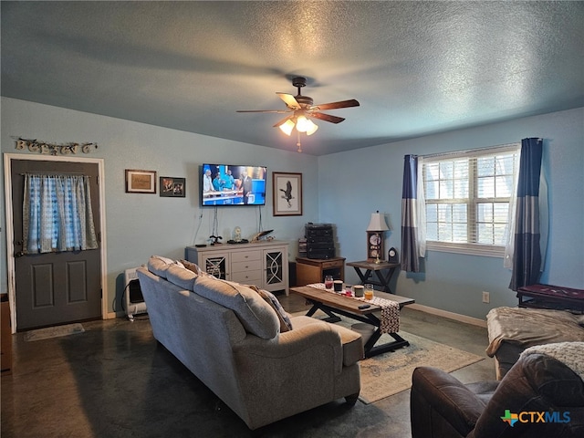 living room with baseboards, a ceiling fan, and a textured ceiling