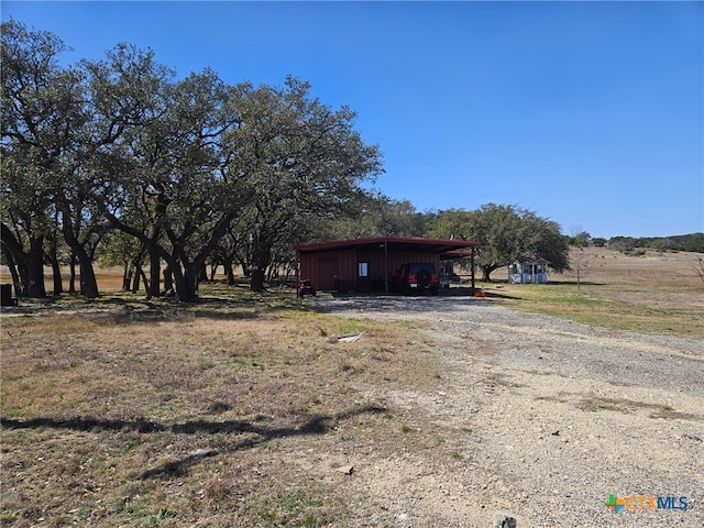 exterior space featuring driveway, a detached carport, and an outbuilding