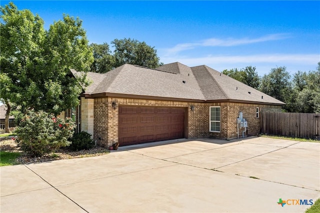 6319 Drexel Loop, Temple, TX 76502 - view of side of property featuring an attached garage, brick siding, concrete driveway, and a shingled roof