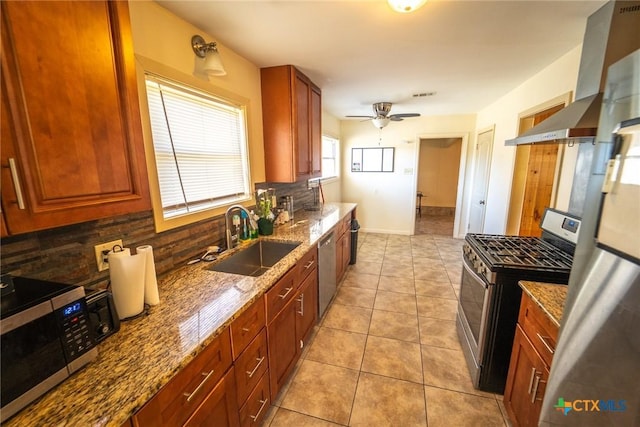 kitchen featuring light stone countertops, sink, ceiling fan, stainless steel appliances, and tasteful backsplash