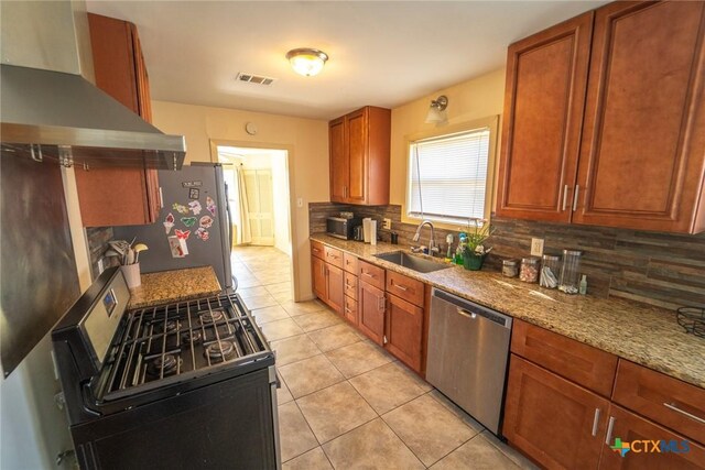 kitchen with sink, wall chimney exhaust hood, light tile patterned floors, tasteful backsplash, and stainless steel appliances