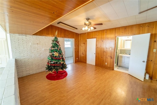 interior space featuring ceiling fan, wooden ceiling, brick wall, wood walls, and hardwood / wood-style flooring