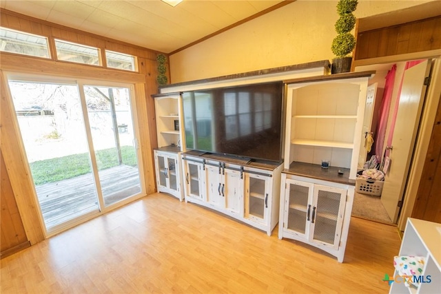 unfurnished living room with wood walls, lofted ceiling, and light hardwood / wood-style flooring