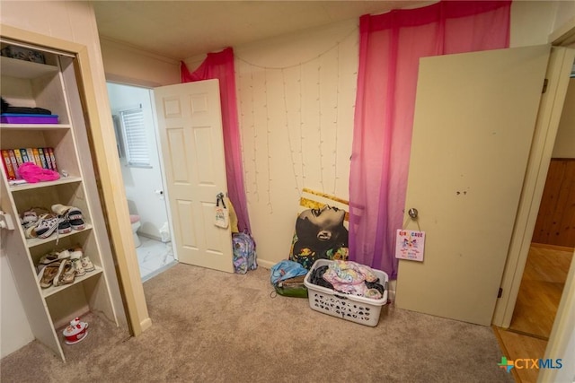 bedroom with light colored carpet and wood walls