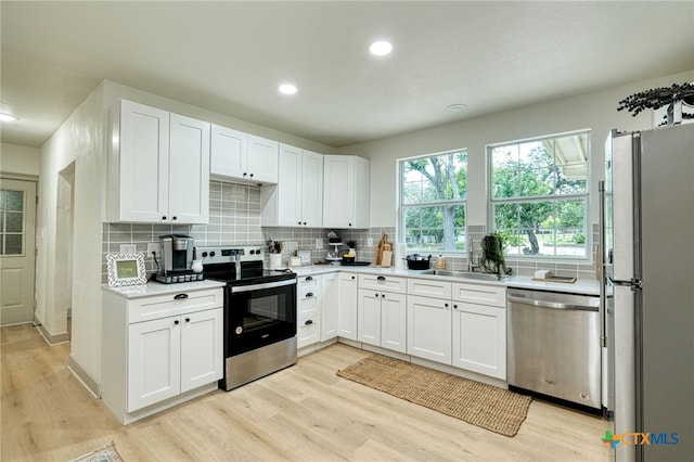 1606 Lone Man Mountain Rd, Wimberley, TX 78676 - kitchen featuring stainless steel appliances, a sink, light wood-style floors, tasteful backsplash, and recessed lighting