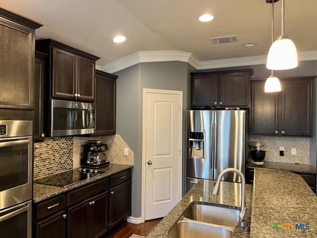 kitchen with sink, dark stone countertops, decorative light fixtures, decorative backsplash, and appliances with stainless steel finishes