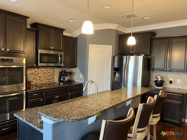 kitchen with decorative light fixtures, a center island, stainless steel appliances, and backsplash