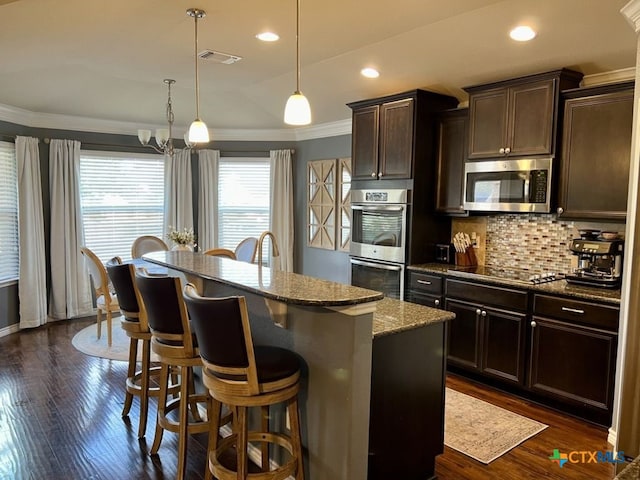 kitchen with pendant lighting, a center island with sink, dark hardwood / wood-style flooring, light stone counters, and stainless steel appliances