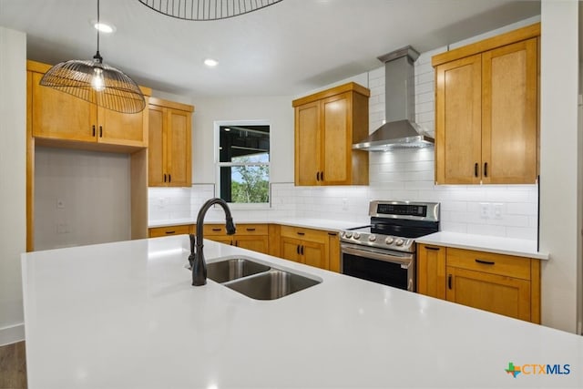 kitchen with sink, tasteful backsplash, decorative light fixtures, stainless steel electric range, and wall chimney range hood