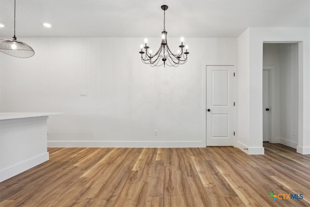 unfurnished dining area featuring wood-type flooring and an inviting chandelier