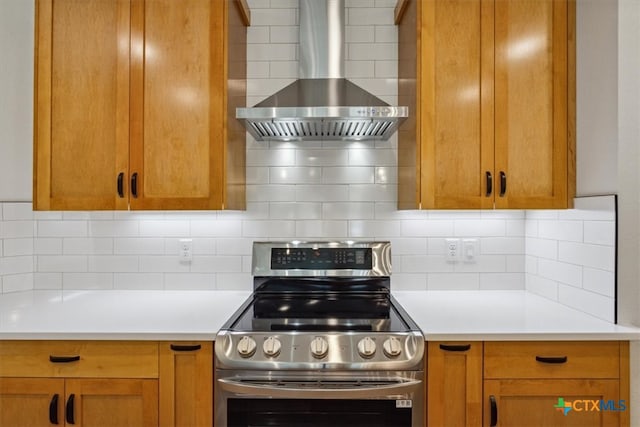 kitchen featuring stainless steel range, decorative backsplash, and wall chimney range hood