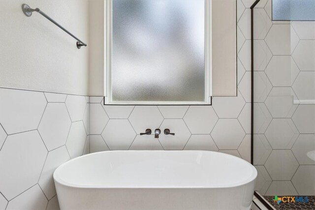 bathroom with tile walls and a bath