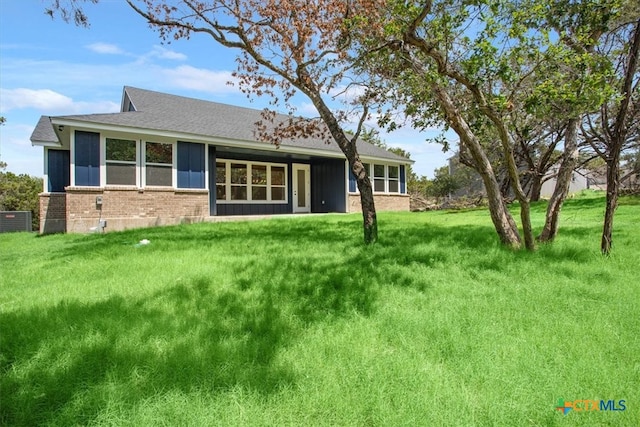 back of house with central AC unit and a yard