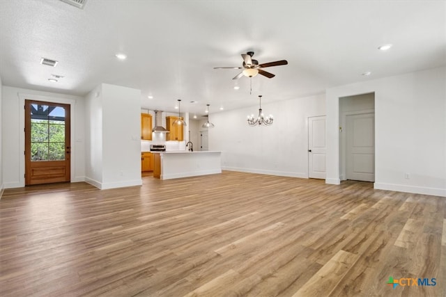 unfurnished living room with light wood-type flooring, ceiling fan with notable chandelier, a textured ceiling, and sink