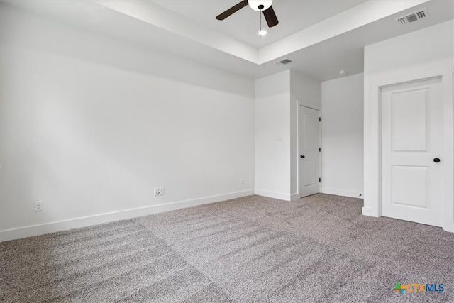 unfurnished bedroom with ceiling fan, a raised ceiling, and carpet floors