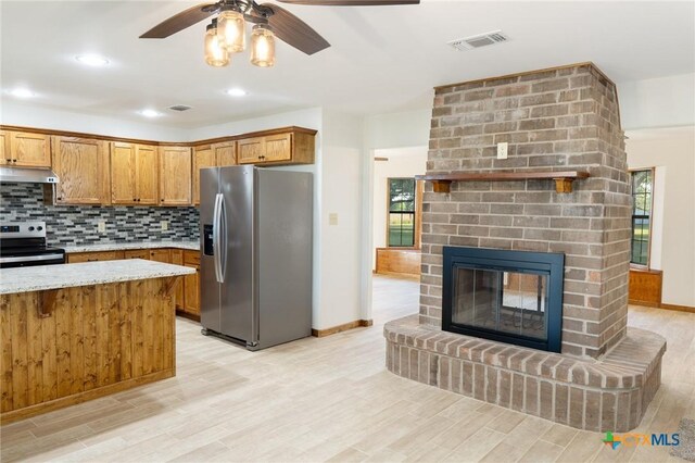 kitchen featuring visible vents, stainless steel appliances, under cabinet range hood, and brown cabinetry