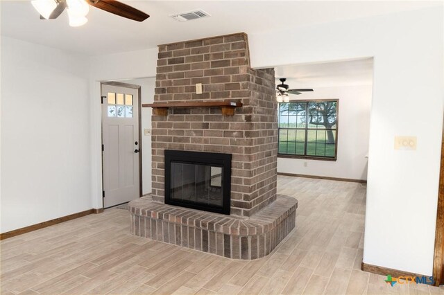 unfurnished living room featuring a wealth of natural light, a barn door, baseboards, wood finished floors, and ceiling fan