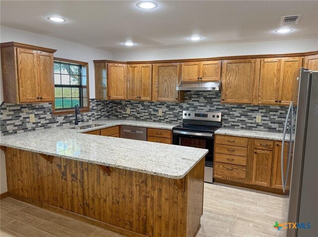 kitchen with under cabinet range hood, visible vents, a sink, a peninsula, and appliances with stainless steel finishes