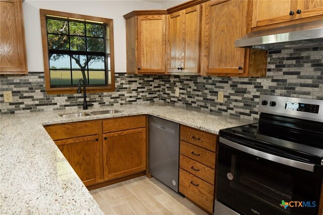 kitchen with stainless steel appliances, a sink, decorative backsplash, brown cabinets, and under cabinet range hood