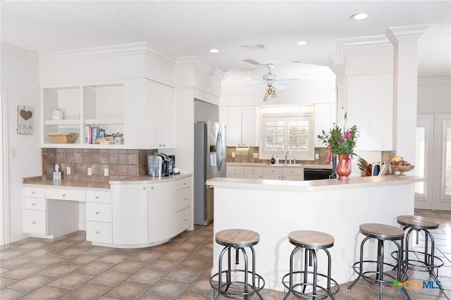 kitchen featuring stainless steel fridge, ornamental molding, a kitchen breakfast bar, a peninsula, and built in desk