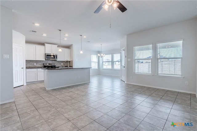 kitchen with stainless steel appliances, light tile patterned floors, an island with sink, and white cabinetry