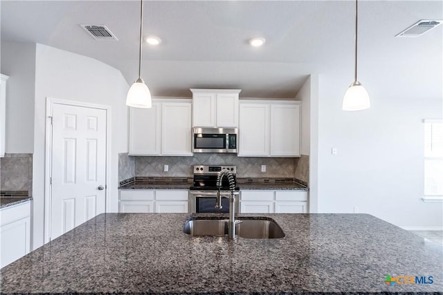 kitchen featuring decorative light fixtures, stainless steel appliances, decorative backsplash, white cabinets, and dark stone counters