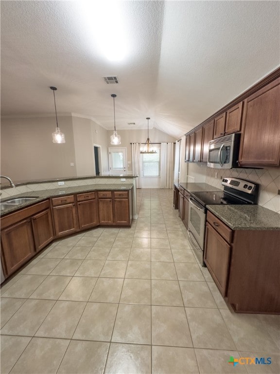 kitchen featuring sink, appliances with stainless steel finishes, a chandelier, pendant lighting, and vaulted ceiling