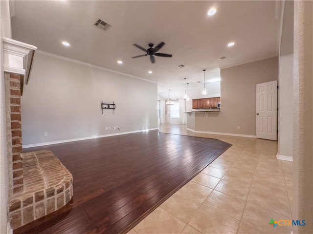 unfurnished living room featuring light wood-type flooring, ceiling fan with notable chandelier, and crown molding