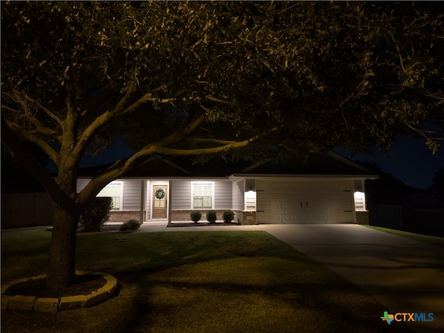 ranch-style home featuring a garage and a lawn