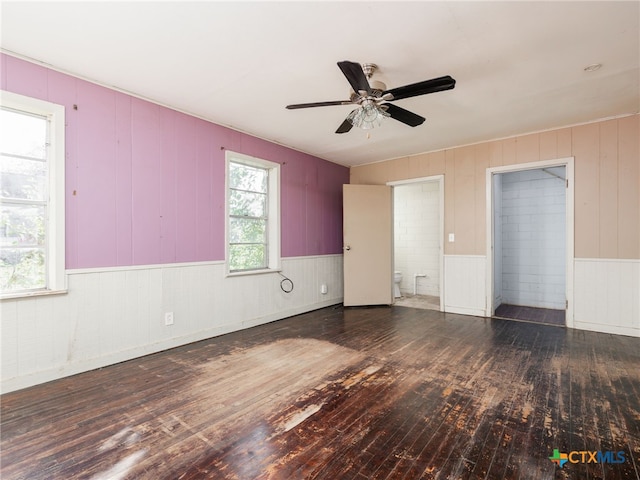 spare room with ceiling fan, dark wood-type flooring, and wood walls