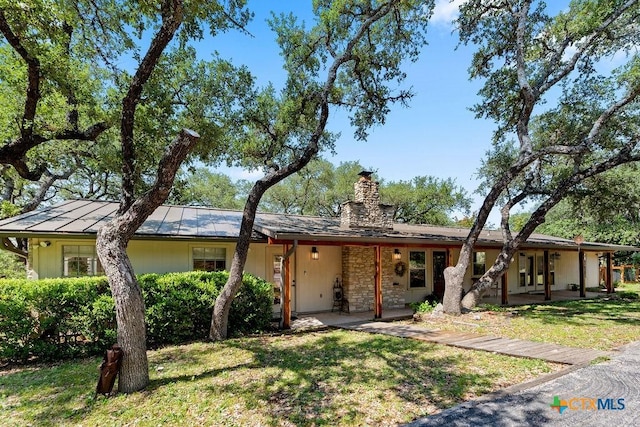 200 W Meadow Ln, Wimberley, TX 78676 - view of front of house featuring a chimney, a front yard, a standing seam roof, and metal roof