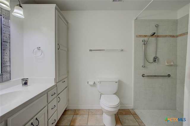 bathroom featuring toilet, vanity, tile patterned flooring, and tiled shower