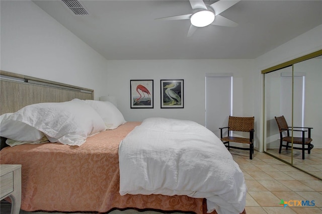 tiled bedroom with ceiling fan and a closet