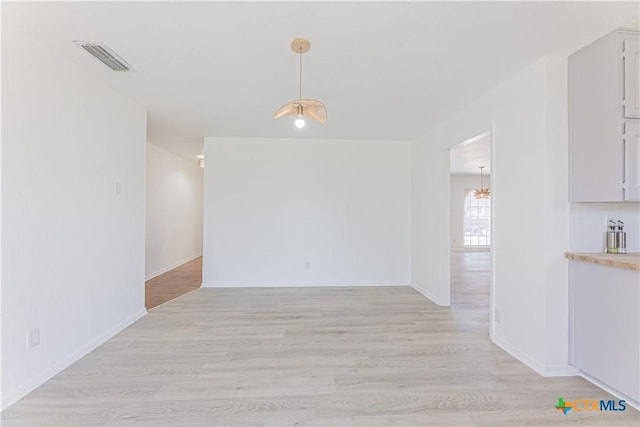 unfurnished dining area featuring light wood-style flooring and visible vents