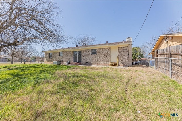 rear view of property with a yard, fence, brick siding, and entry steps