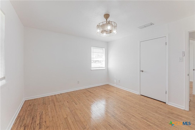 unfurnished room featuring wood finished floors, visible vents, and baseboards