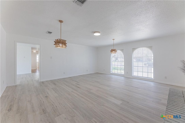 spare room with visible vents, baseboards, a textured ceiling, and light wood-style flooring