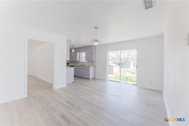 unfurnished living room featuring a sink, baseboards, and light wood-style floors